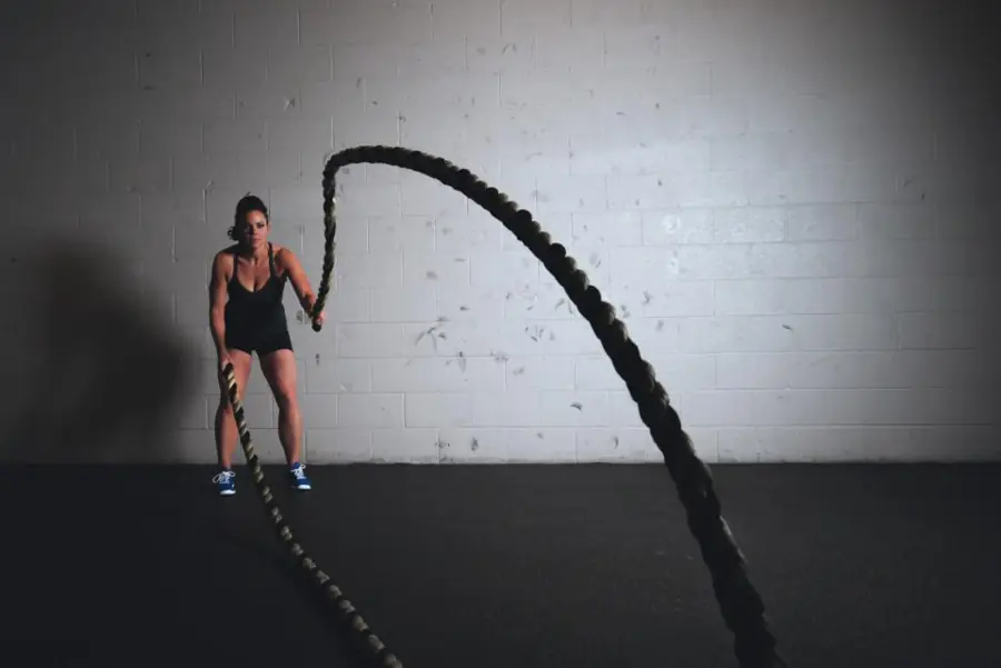 Mujer entrenando con cuerdas de batalla