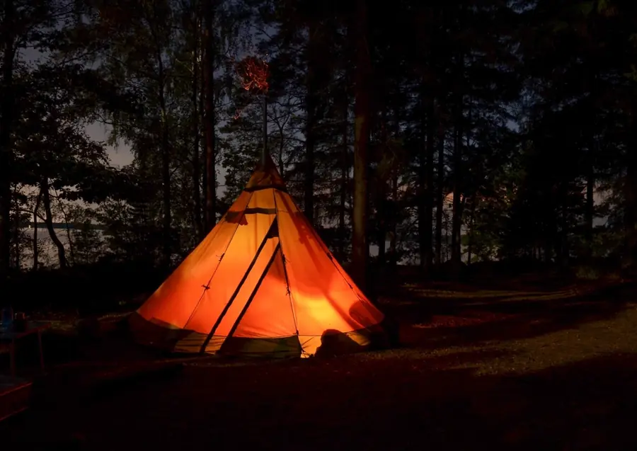 Carpa glamping iluminada en medio del bosque de noche