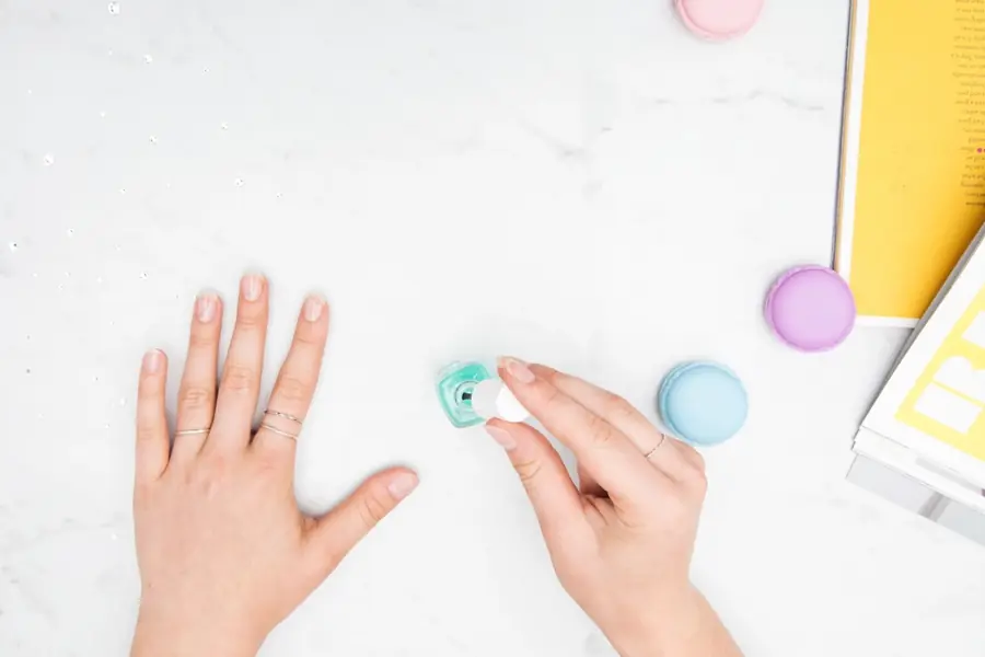Manos sobre mesa de manicure con esmaltes